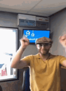 a man wearing a hat and a yellow shirt is dancing in front of a tv screen that says radio