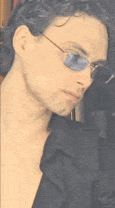 a man wearing sunglasses and a black shirt looks to the side