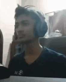 a young man wearing headphones is sitting at a table in a room .