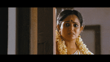 a woman with a flower garland around her neck is standing in front of a door with simply south written on the bottom