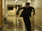 a man running down a hallway with a clock on the wall behind him