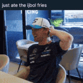 a man wearing a hat with the letter g on it is sitting at a table