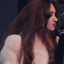 a woman in a fur coat sings into a microphone that says rode on it