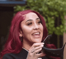 a woman with red hair is wearing sunglasses and smiling .
