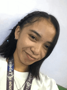 a girl wearing a lanyard that says lspsco smiles for the camera