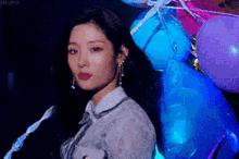 a woman is standing in front of a bunch of blue and pink balloons .