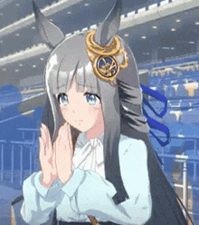 a girl with long hair and horns is standing in a stadium with her hands together .