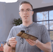 a young man wearing glasses is holding a wallet