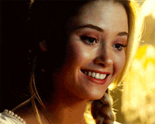 a close up of a woman 's face smiling with a braid