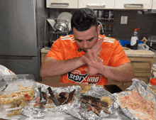 a man in an orange shirt that says ' sdrxmo ' on it