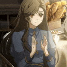 a girl is sitting at a table with her hands folded .