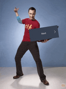 a man in a red shirt is holding a box that says next on it
