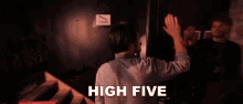 a man is giving another man a high five while standing in a dark room .