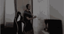 a man is playing a video game in a living room while wearing headphones and a pink and black gaming chair