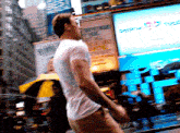 a man in a white shirt is walking down a street in front of a sign that says ' subway '