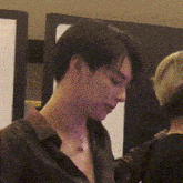 a man wearing a black shirt and a necklace looks down