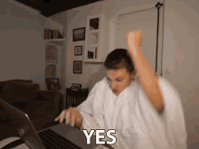 a person sitting in front of a laptop with the word yes written on the screen
