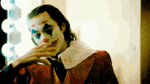 a man in a clown costume is smoking a cigarette in front of a mirror
