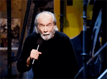 a man with a beard is holding a microphone and making a funny face