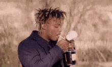 a man in a suit is smoking a cigarette while holding a bottle of liquor .