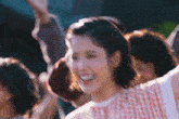 a woman is standing in front of a crowd with her arms in the air and smiling .