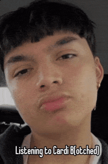 a young man making a funny face with the caption listening to cardi b