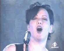 a woman singing into a microphone with the mediaset logo on the bottom right