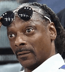 a close up of snoop dogg wearing sunglasses on his head .