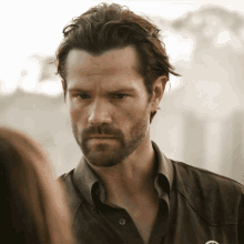 a man with a beard is wearing a brown shirt with a badge that says sheriff on it