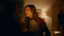 a woman is dancing in a dark room with a bet logo in the background