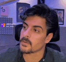 a man with a beard is sitting in a chair making a funny face .