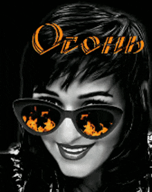 a black and white photo of a woman wearing sunglasses with a reflection of flames in the lenses