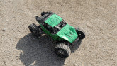 a green rc car is driving down a dirt road .