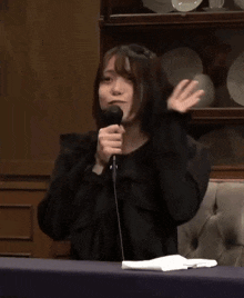 a woman sitting at a table with a microphone in her hand