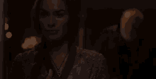 a woman is wearing a necklace and standing in a dark room .