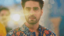 a man with a beard is wearing a colorful shirt and looking at the camera .