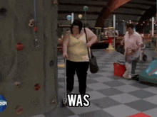 a woman in a yellow tank top is walking with a cane and the word was is on the floor in front of her
