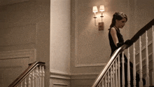 a woman in a black dress is walking down stairs