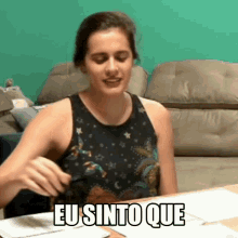 a woman is sitting at a table with the words eu sinto que written on it