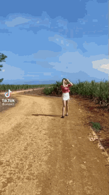 a woman is running down a dirt road in a field .