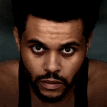 a close up of a man 's face with a beard and a black tank top