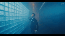 a man in a tuxedo is standing in front of a wall of glass tiles