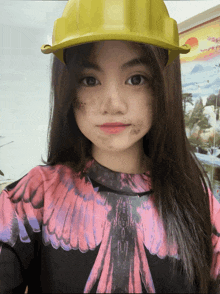 a young girl wearing a yellow hard hat
