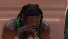 a basketball player wearing a green jersey with the word adidas on it