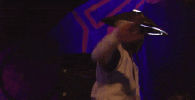 a man wearing a mask and a hat is dancing in front of a purple background