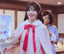 a woman is wearing a pink cape with a red bow and smiling