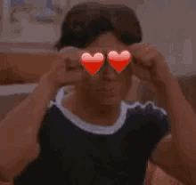 a young man wearing heart shaped glasses is giving the middle finger .