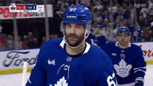 a hockey player wearing a number 67 jersey stands on the ice