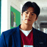 a man wearing a blue jacket and a red sweater has a name tag that says ' 박우민 '