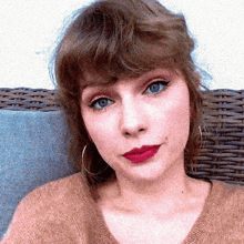 a woman with blue eyes and red lipstick is sitting on a couch .
